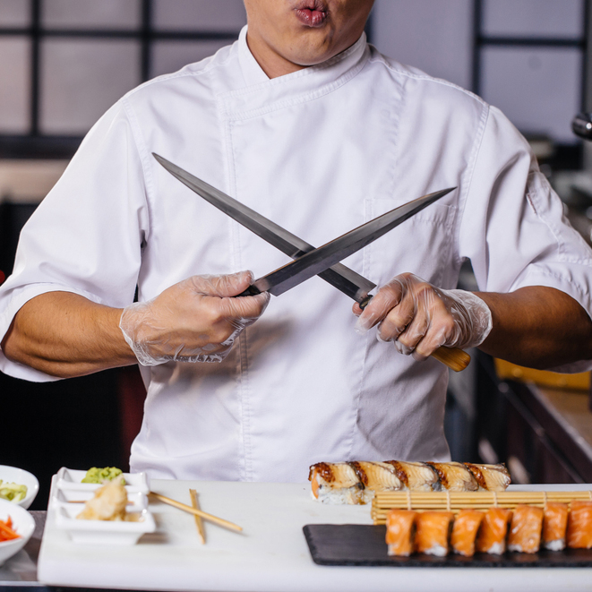 man in white uniform with crossed . close up cropped photo. sharp knives for cooking